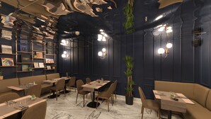 Een restaurantinterieur met zitjes, tafels en hangplanten.