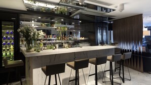 Een moderne bar met een marmeren aanrecht, barstoelen en diverse flessen en glazen.