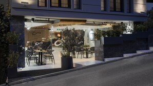 Een modern gebouw met een glazen gevel, terrasplekken en potplanten.