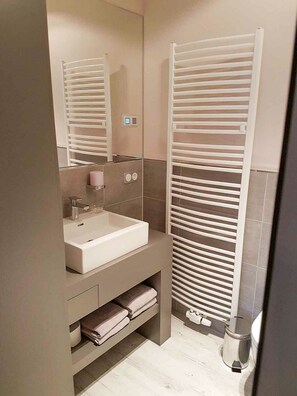 A modern bathroom with a white sink, mirror, and towel rack. - Die Hütten 550 üNN (Braunlage)