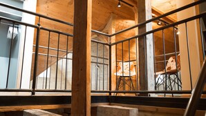 A wooden interior with a staircase, metal railings, and a chair. - Die Hütten 550 üNN (Braunlage)