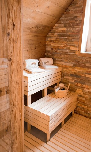 A wooden sauna room with benches and towels labeled 'SAUNA'. - Die Hütten 550 üNN (Braunlage)