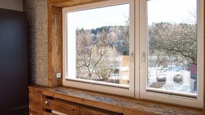 A room with a large window, wooden wall paneling, and a view of a snowy landscape. - Die Hütten 550 üNN (Braunlage)