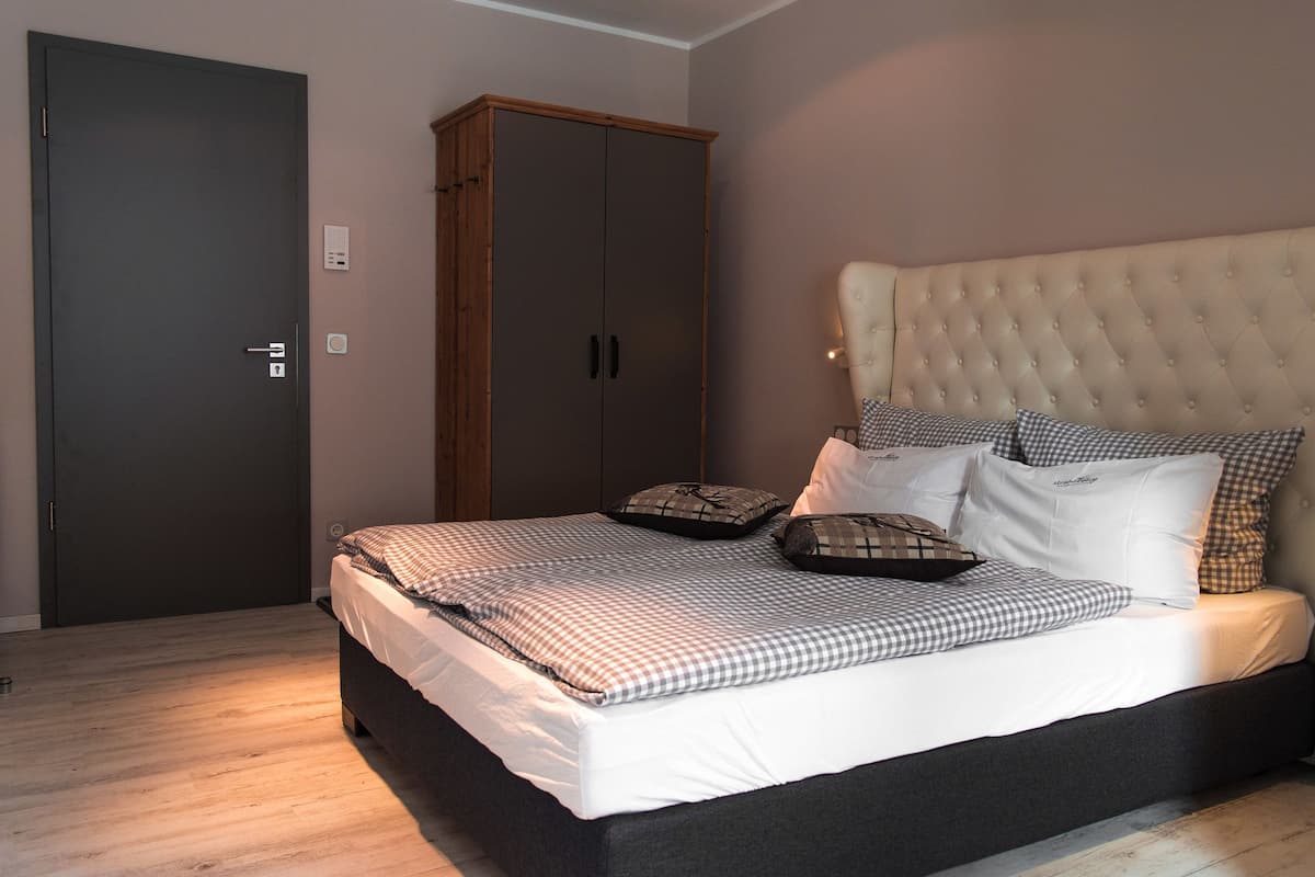 Un dormitorio con cama, armario y cabecera.