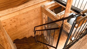 A wooden staircase with metal railings inside a building. - Die Hütten 550 üNN (Braunlage)