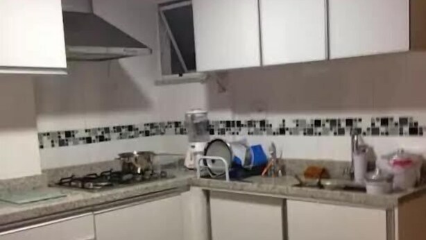 Une cuisine compacte avec des meubles blancs, une cuisinière à gaz, un four à micro-ondes et un dosseret carrelé.