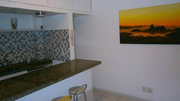Una cocina con salpicadero de azulejos, un lavabo y un cuadro de una puesta de sol.