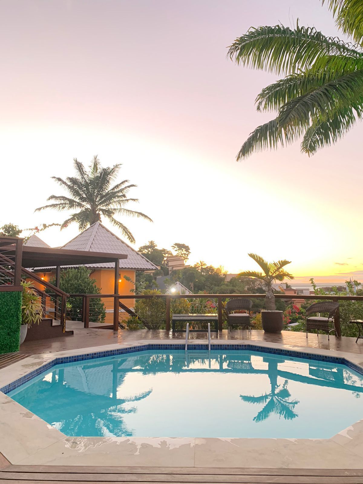 Una piscina con un pabellón, palmeras y vistas al atardecer.