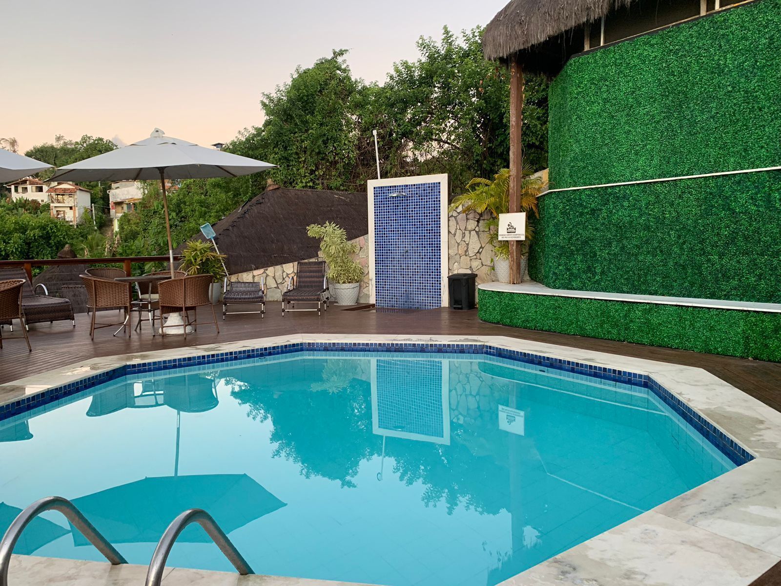 A swimming pool with a tiled edge, surrounded by lounge chairs and umbrellas.