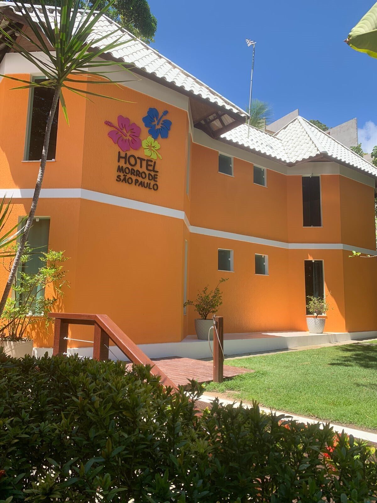 A two-story building with a sign reading "HOTEL MORRO DE SAO PAULO" and colorful flower decorations.