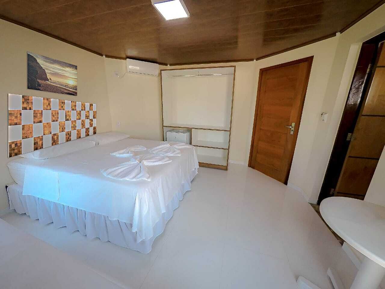 A large, neatly arranged room with a long bed, a small table, and a door.