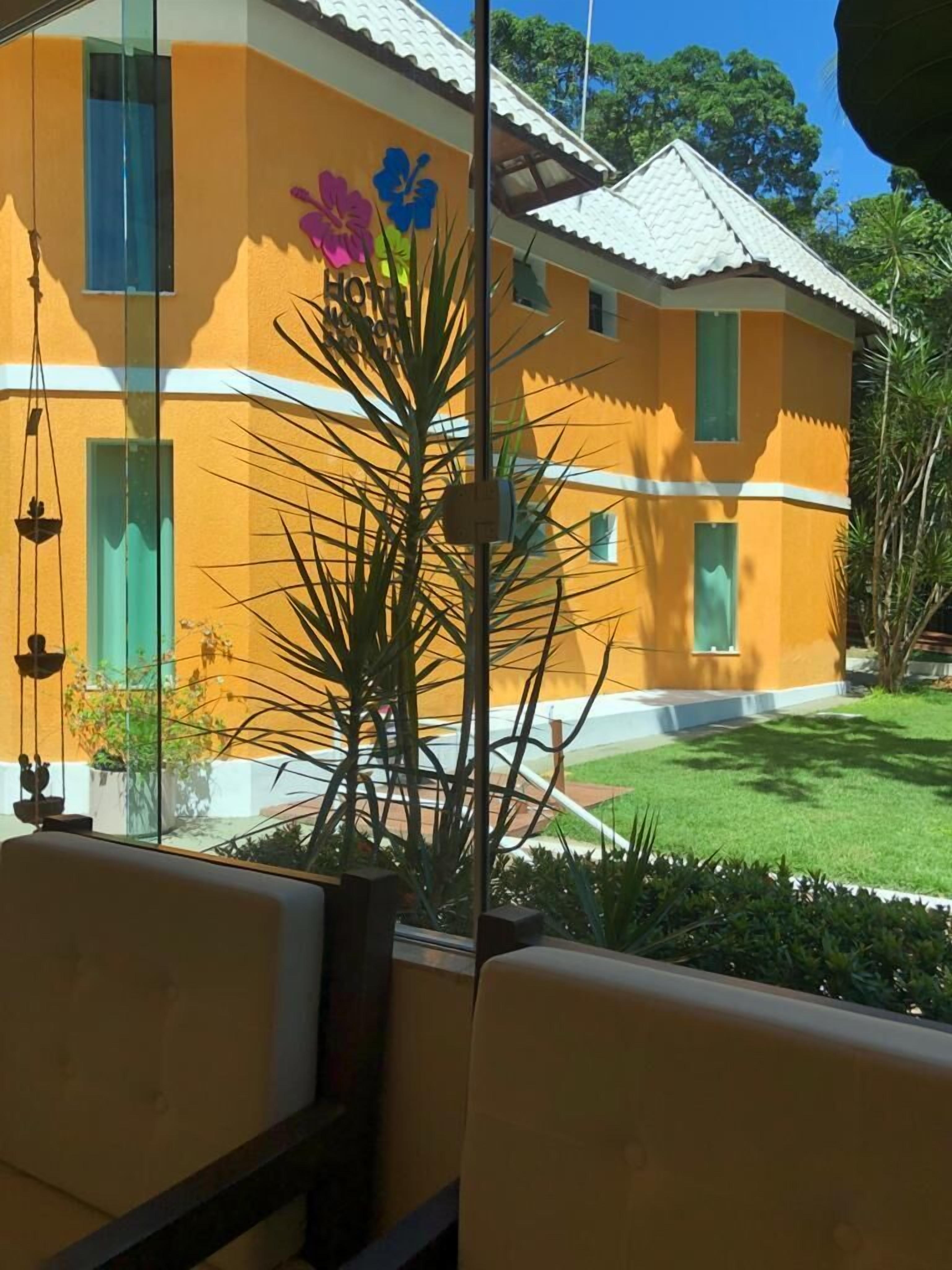 A yellow building with a sign that reads "HOTEL" and a flower decoration.