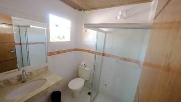 A bathroom with a sink, toilet, and glass shower enclosure.