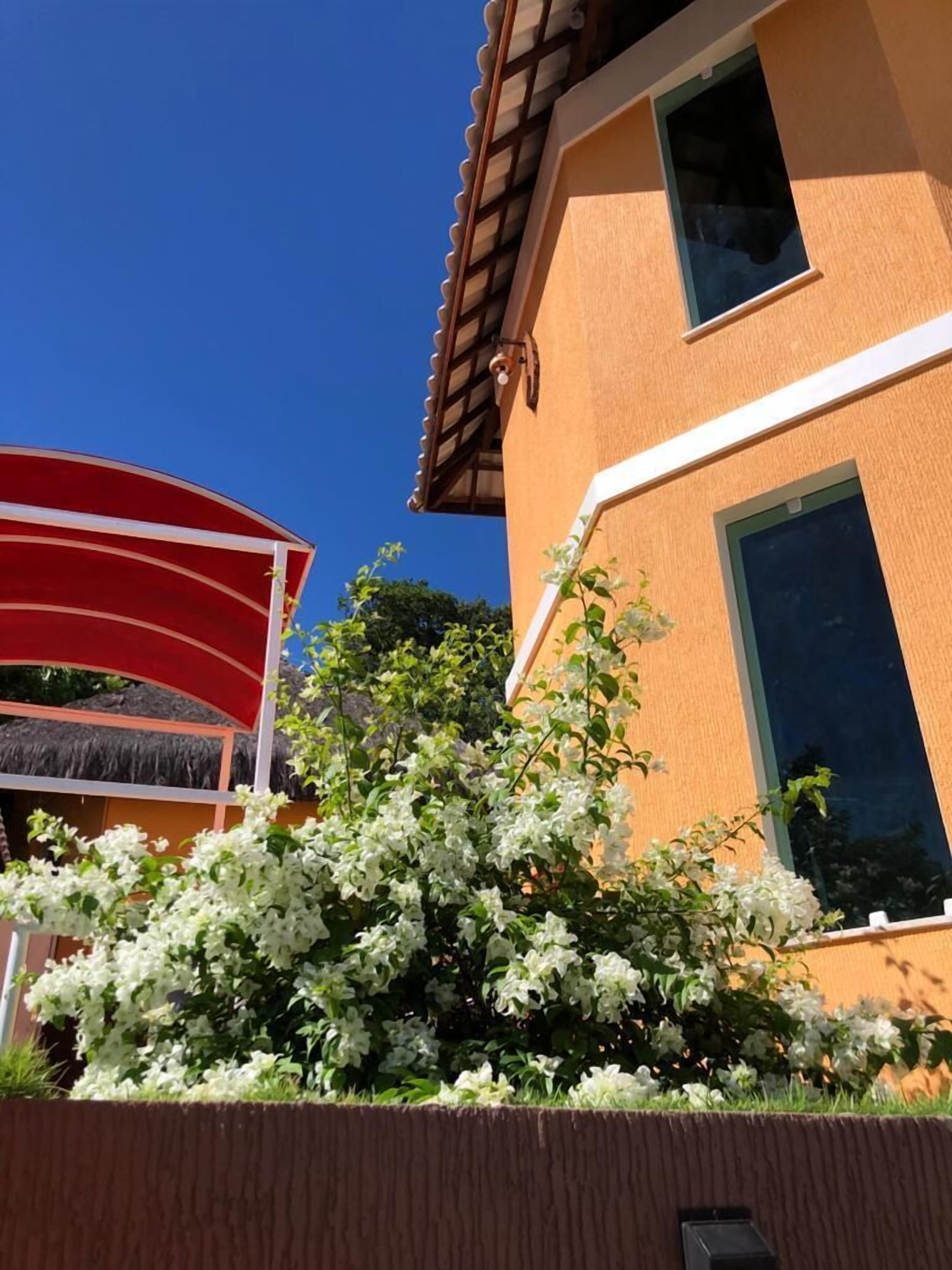 Un edificio con un toldo rojo y plantas blancas florecientes en primer plano.