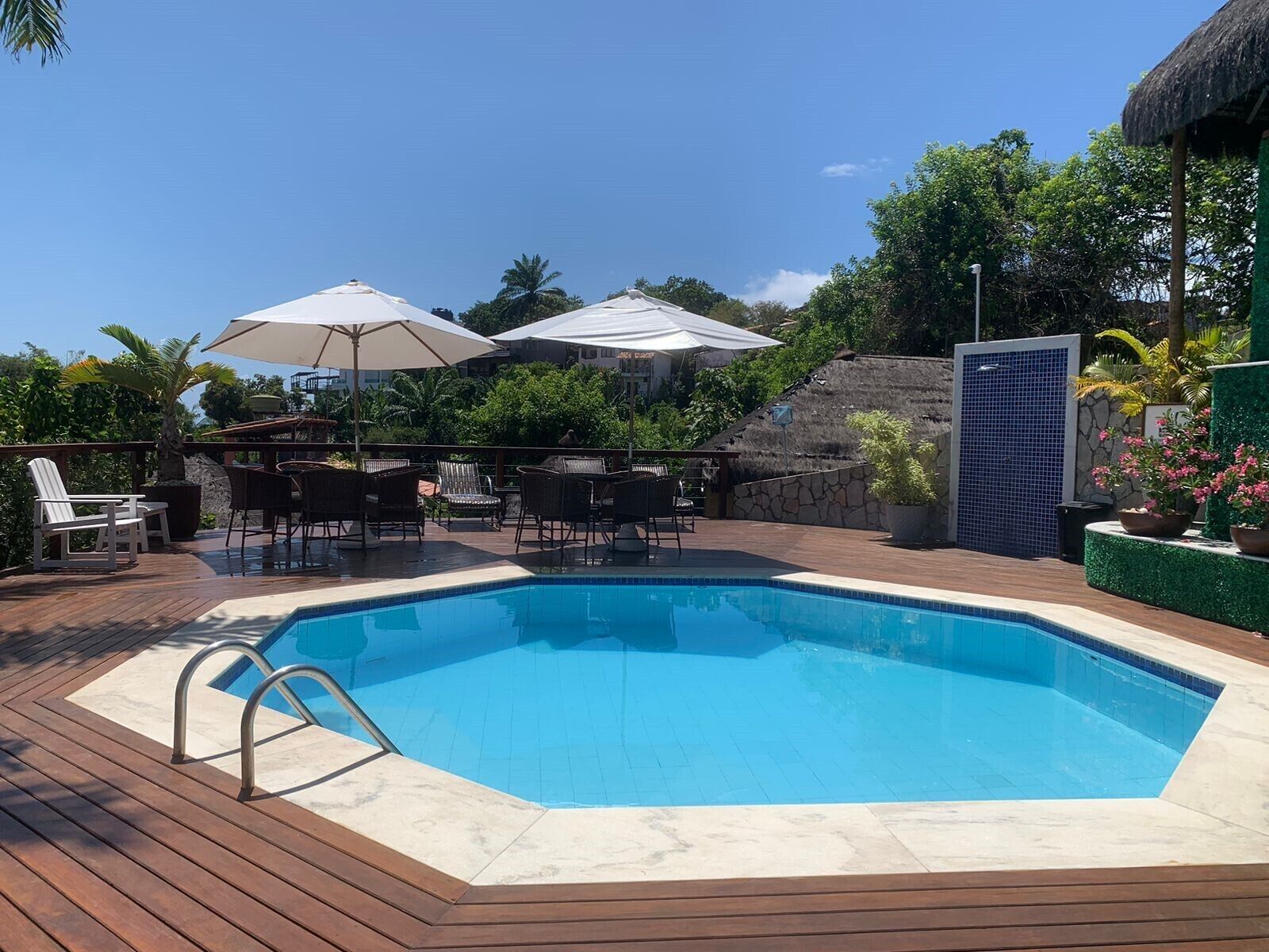 A swimming pool with a wooden deck, lounge chairs, and umbrellas.
