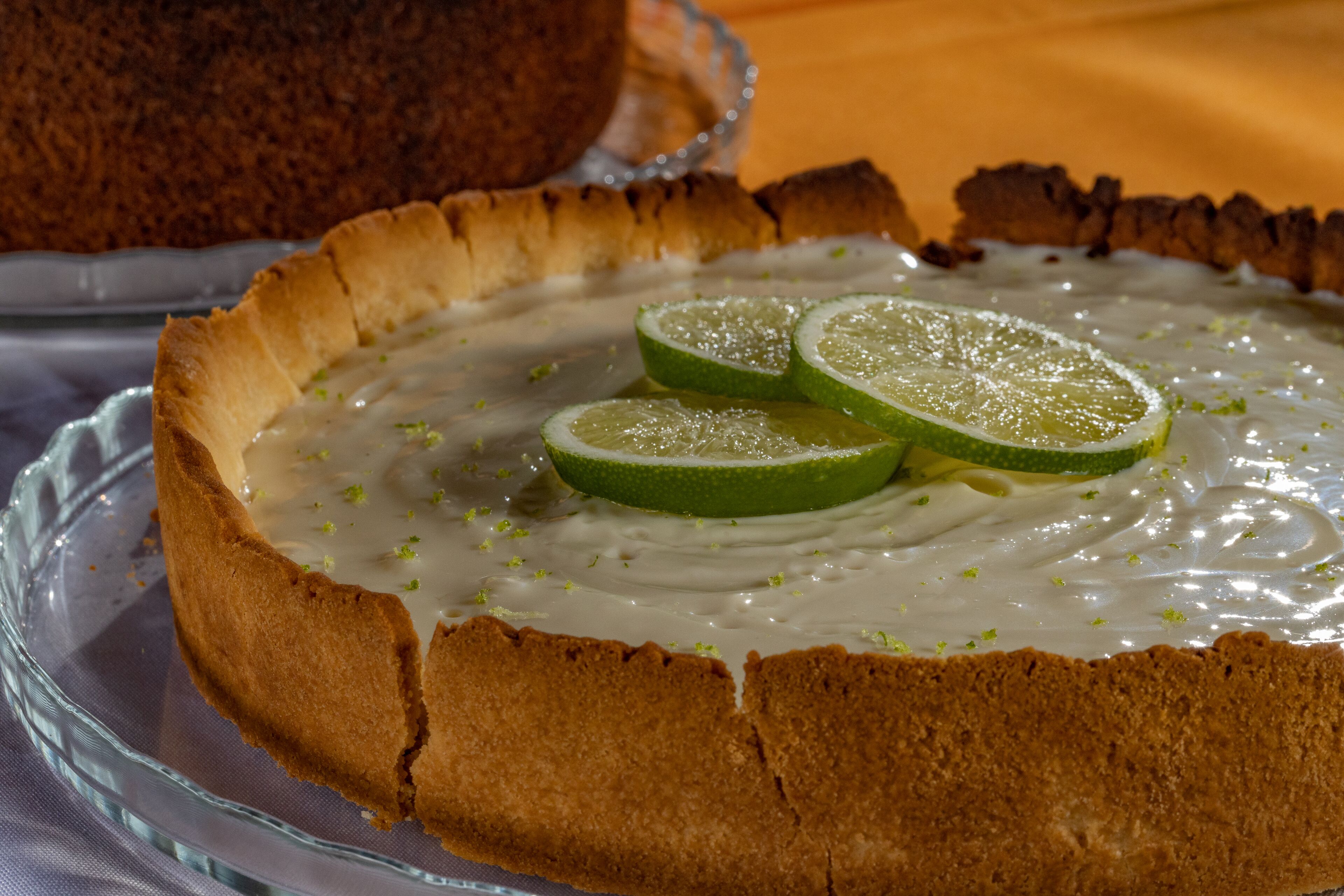Un pastel con rodajas de lima encima, sobre un plato de vidrio.