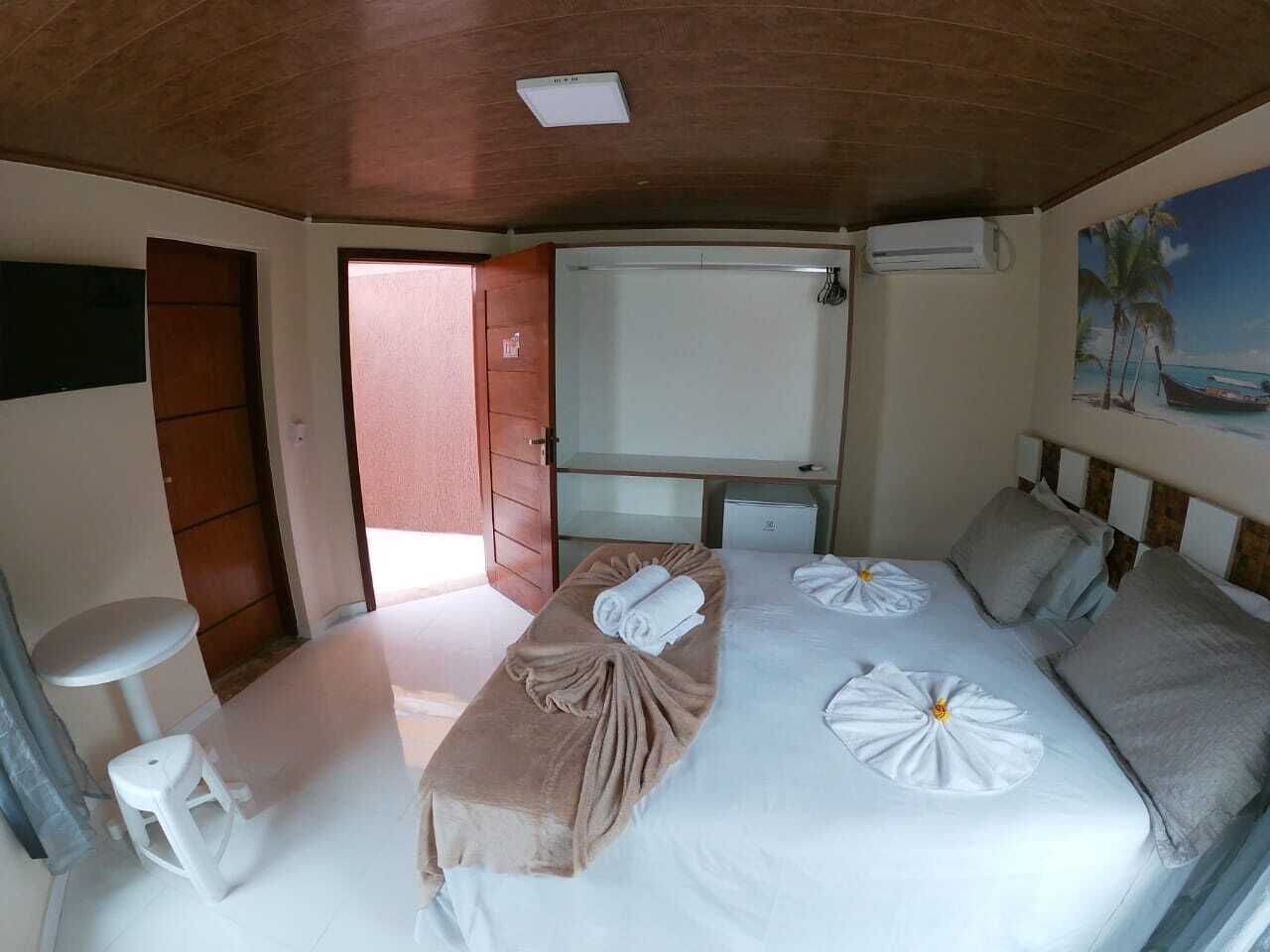 Habitación de hotel con cama, una mesita, un banco, televisor y un cuadro en la pared.