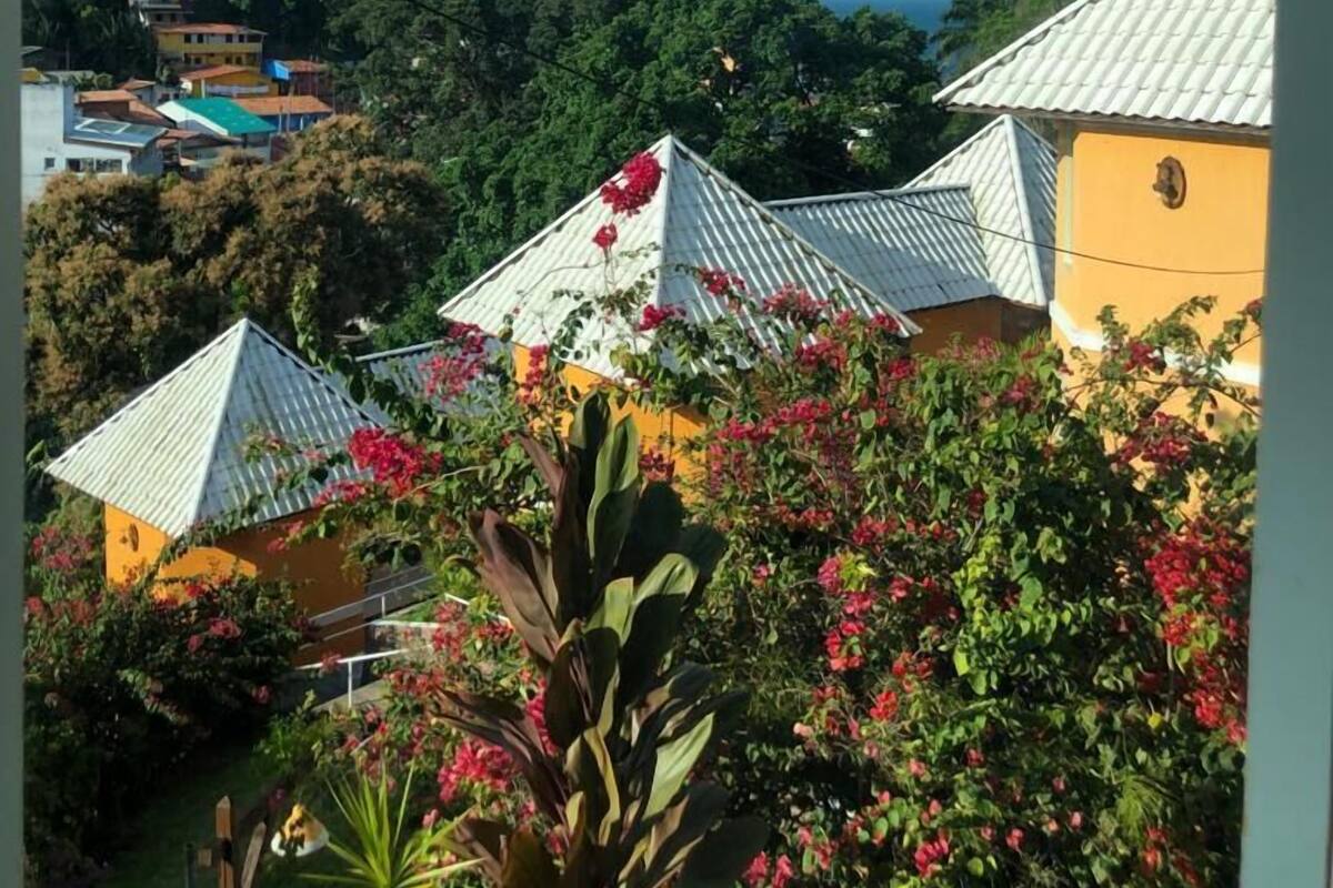 A view of buildings with white roofs and a lighthouse in the background.