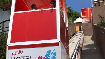 A red and white cable car with "NOVO HOTEL MORRO DE SÃO PAULO" written on the side, moving along a track.