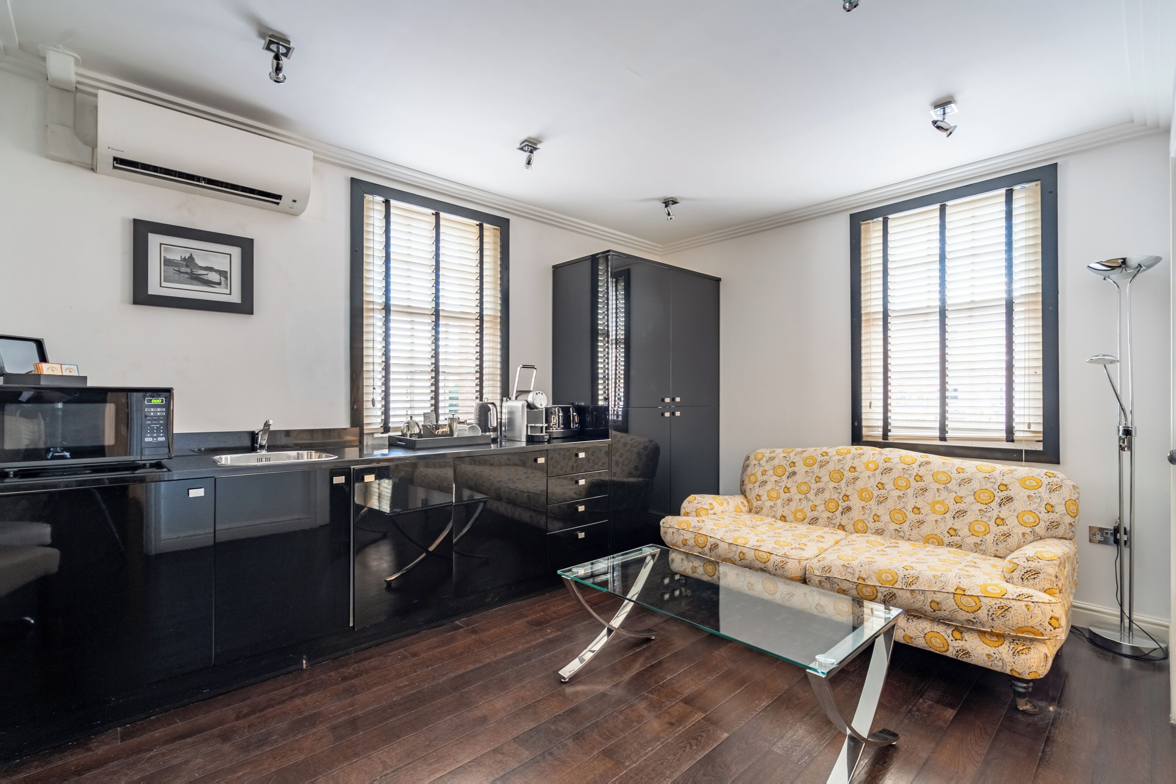 A modern kitchen with a black countertop, a glass coffee table, and a patterned sofa.