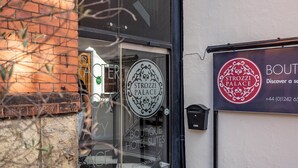 Entrada de un hotel boutique con puerta de vidrio, un cartel que dice "Strozz Palace Boutique Hotel Suites" y un número de contacto.