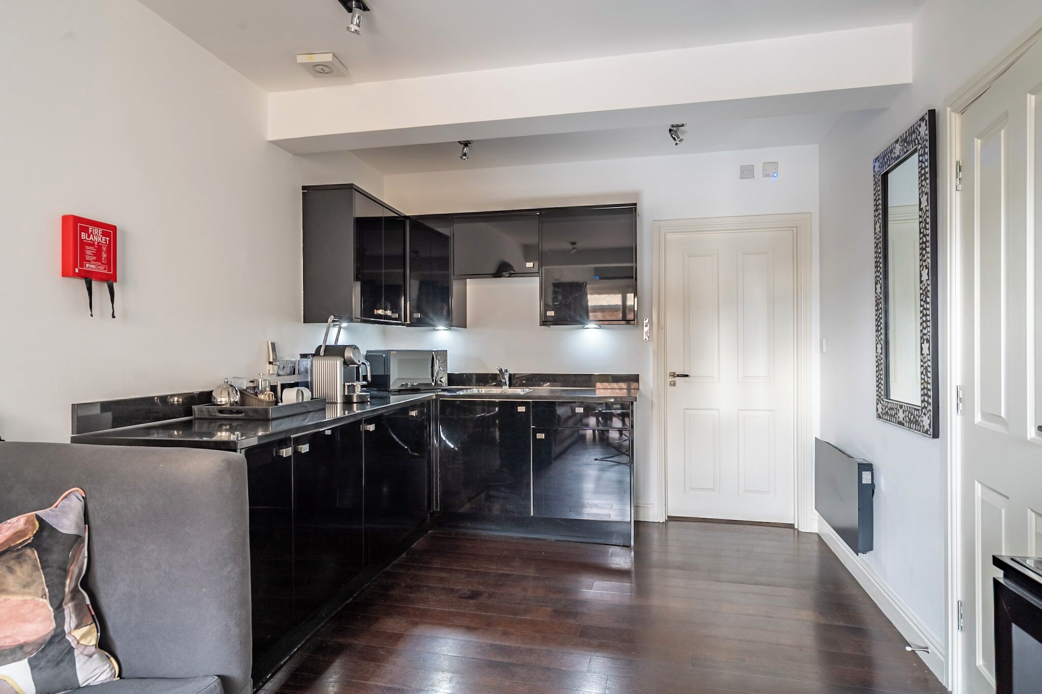 A modern kitchen with black cabinetry, a central island, and a red fire extinguisher on the wall.