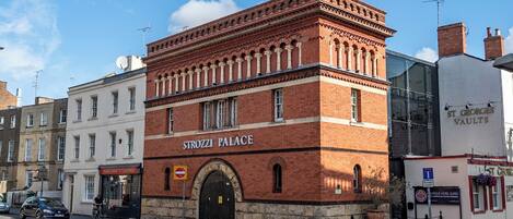 A historic building with a prominent arched entrance and a sign reading 'Strozzi Palace'.