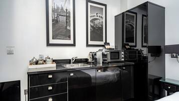 A modern kitchen with a black countertop, stainless steel appliances, and a sink. There are framed pictures on the wall above the counter.
