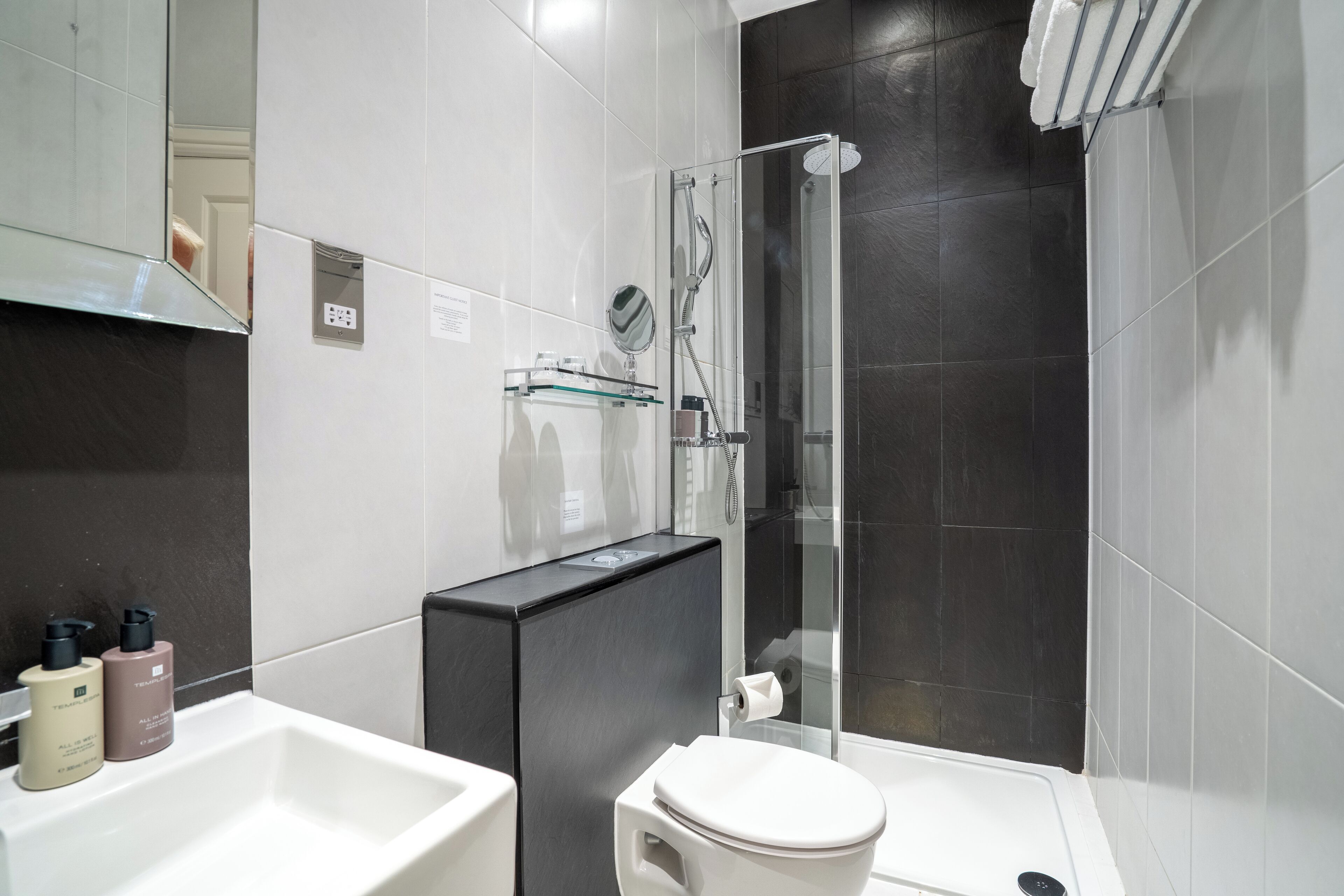Un baño moderno con un lavabo blanco, cabina de ducha de vidrio y un inodoro.
