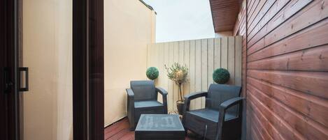 A small outdoor patio with wicker furniture and a potted plant.