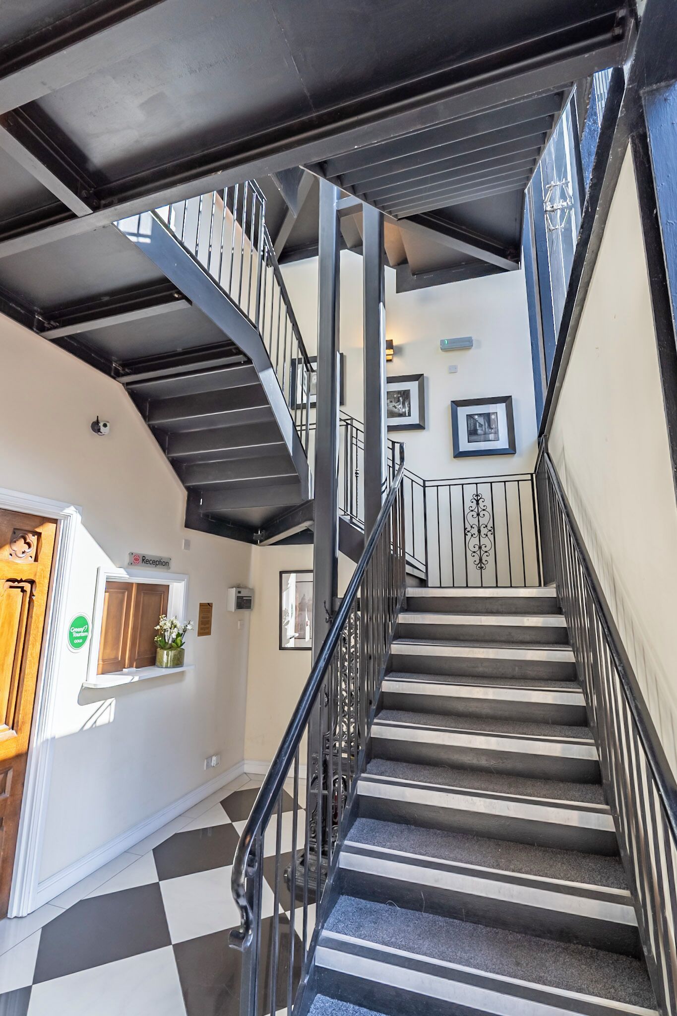 A staircase with a checkered floor, metal railings, and a reception area with a sign.