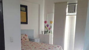 A bedroom with a bed, a nightstand, a mirror, and a window with curtains. - Etours - Lindo 2 Quartos no Coração de Ipanema (Rio de Janeiro)