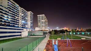 Una cancha deportiva con un tobogán, bancos y una valla.