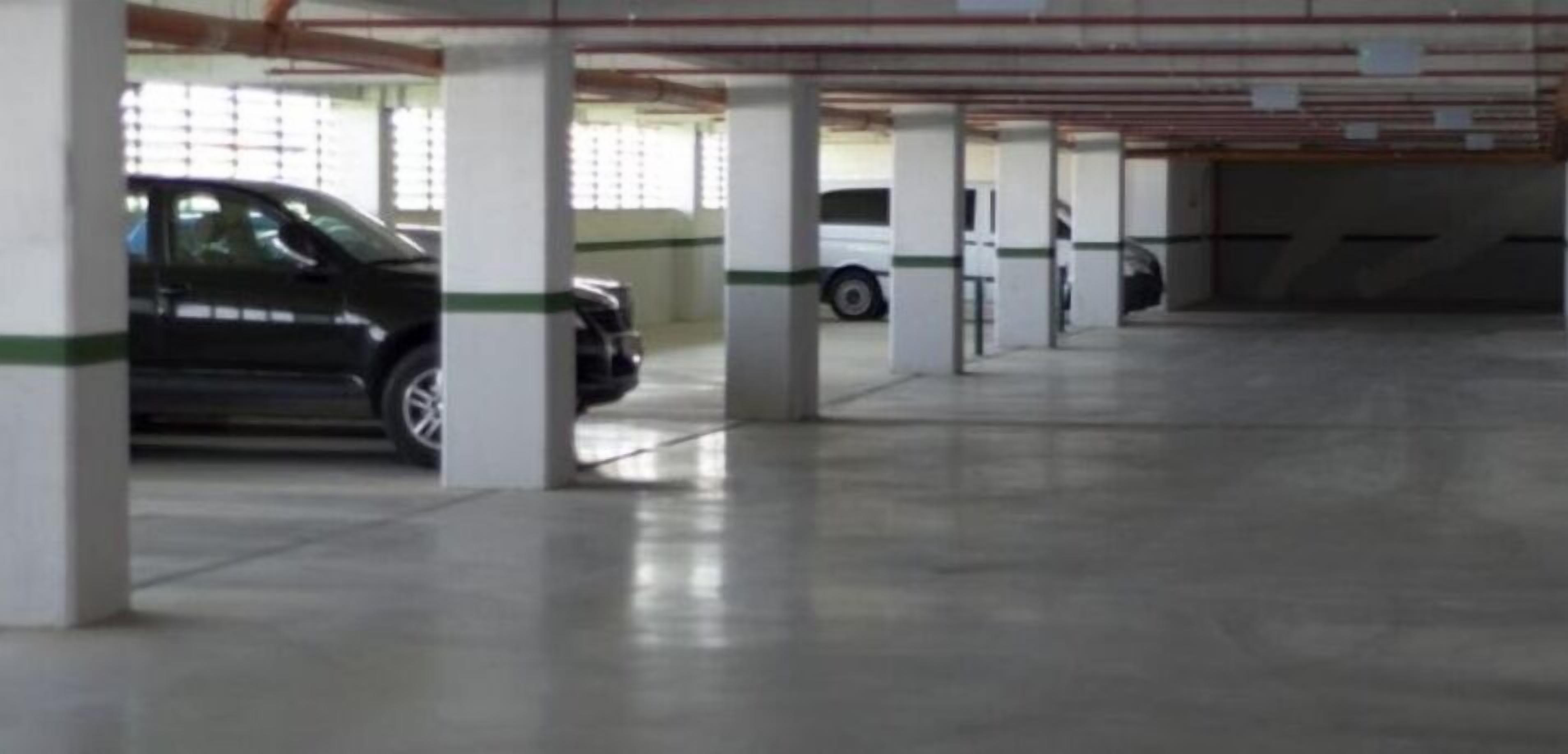 A parking garage with multiple columns and a few parked cars.