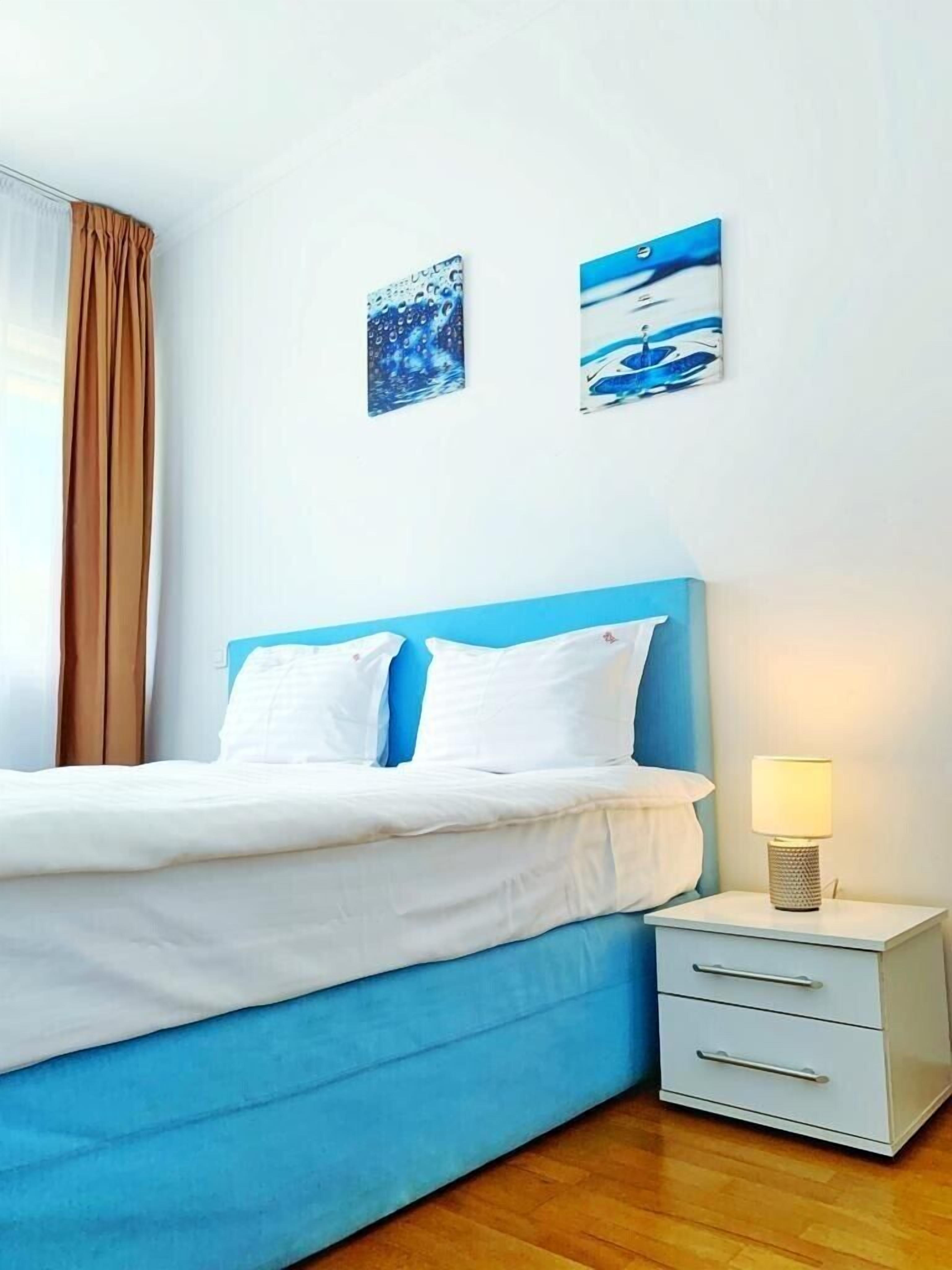 Una camera d'albergo con un letto, un comodino e due opere d'arte a parete.