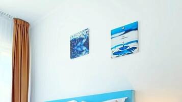 Una camera d'albergo con un letto, un comodino e due opere d'arte a parete.