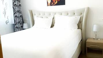 A neatly made bed with white bedding, a headboard, and a bedside table with a lamp.