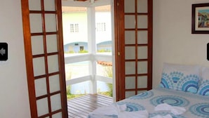 Un dormitorio con una cama, una puerta de madera y vistas a un edificio.