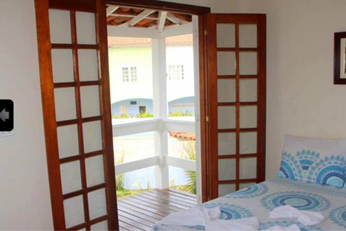 Un dormitorio con una cama, una puerta de madera y vistas a un edificio.