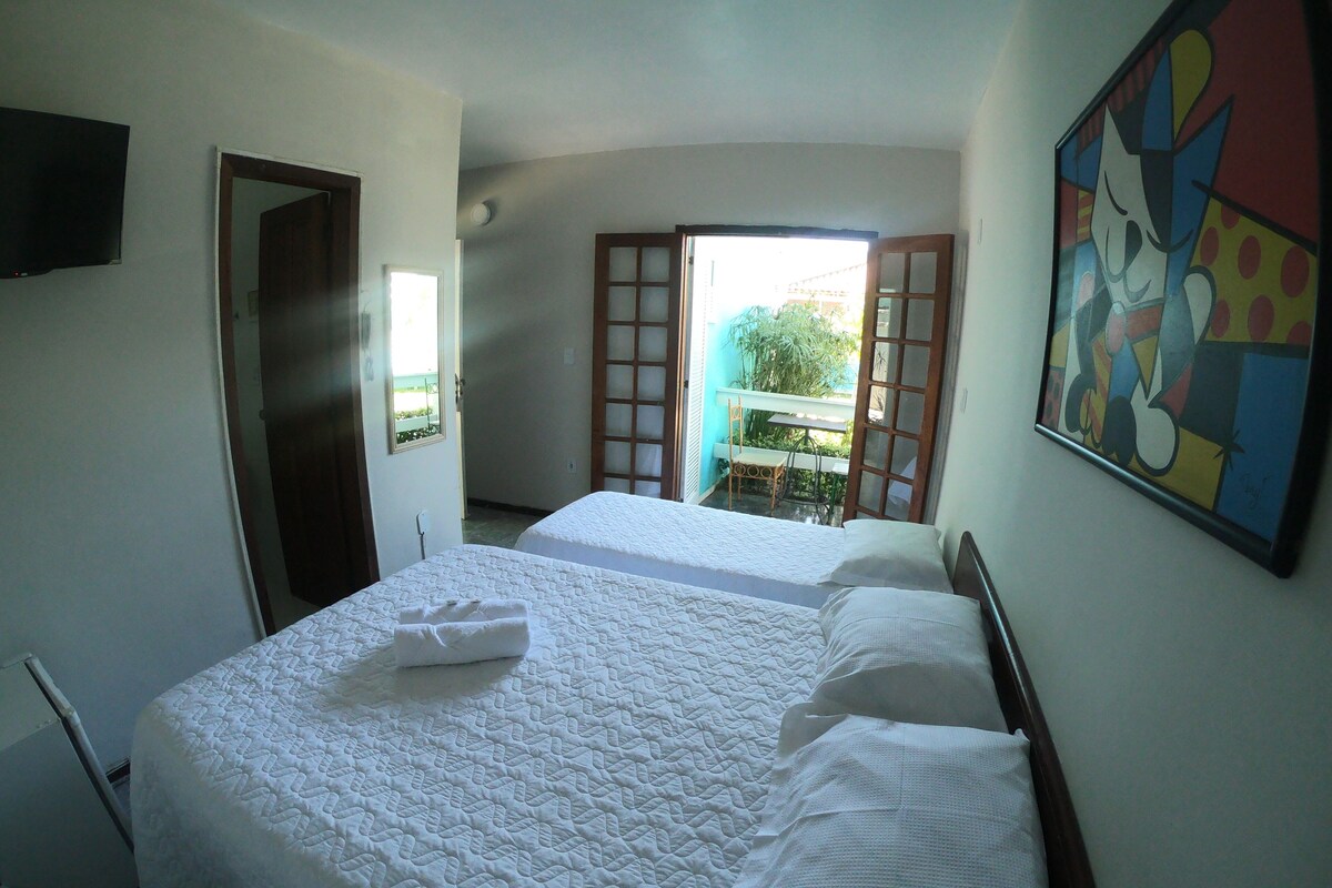 A hotel room with two beds, a TV, and a painting on the wall.