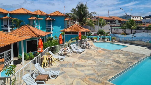 Un resort con piscina, sillones de descanso y un patio con baldosas.