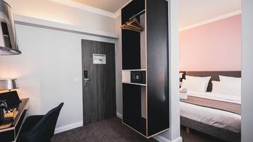 Camera d'albergo con scrivania, sedia, armadio, letto e una parete con orologio.
