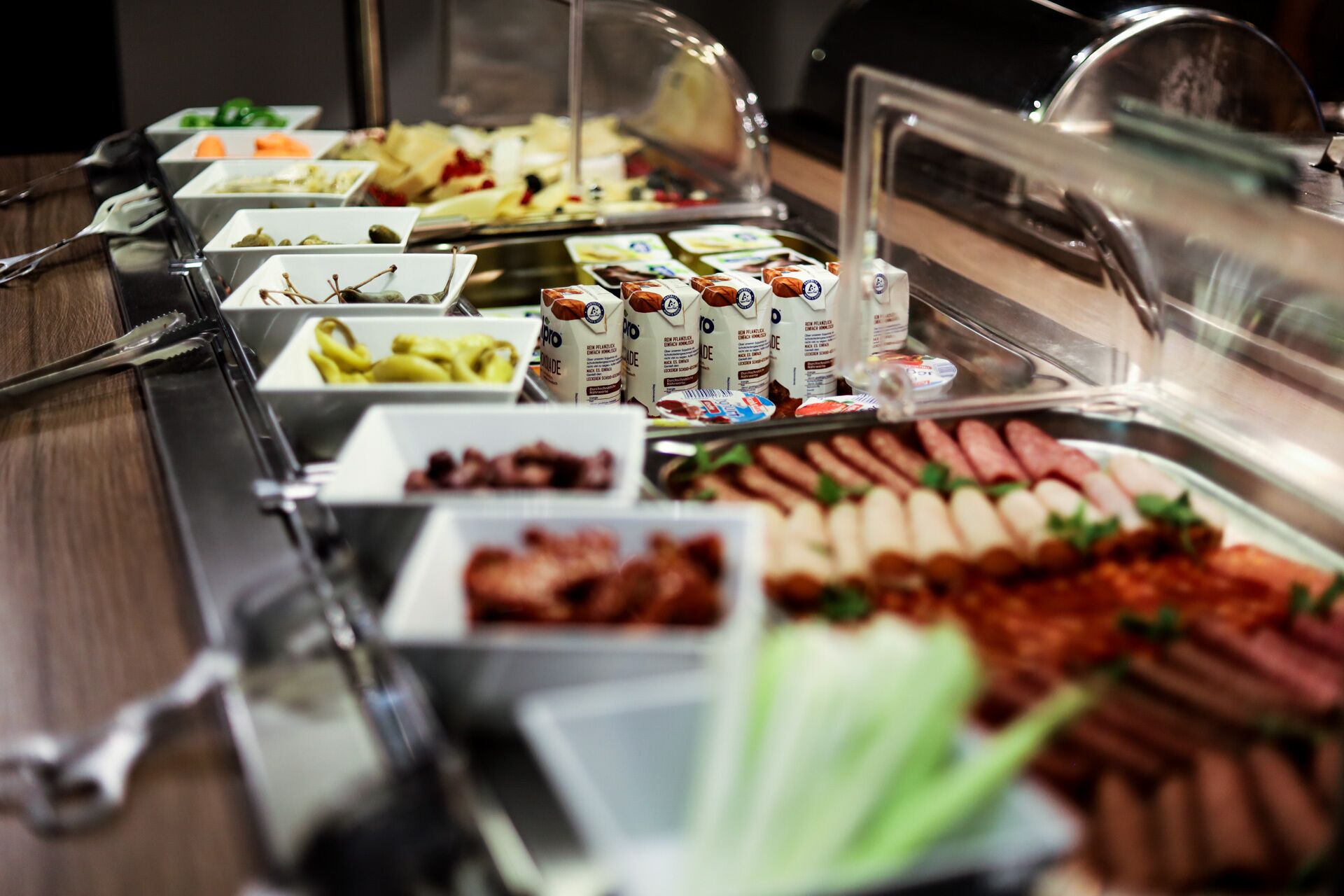 Een buffet met diverse gerechten, waaronder vleeswaren, kazen en sauzen.