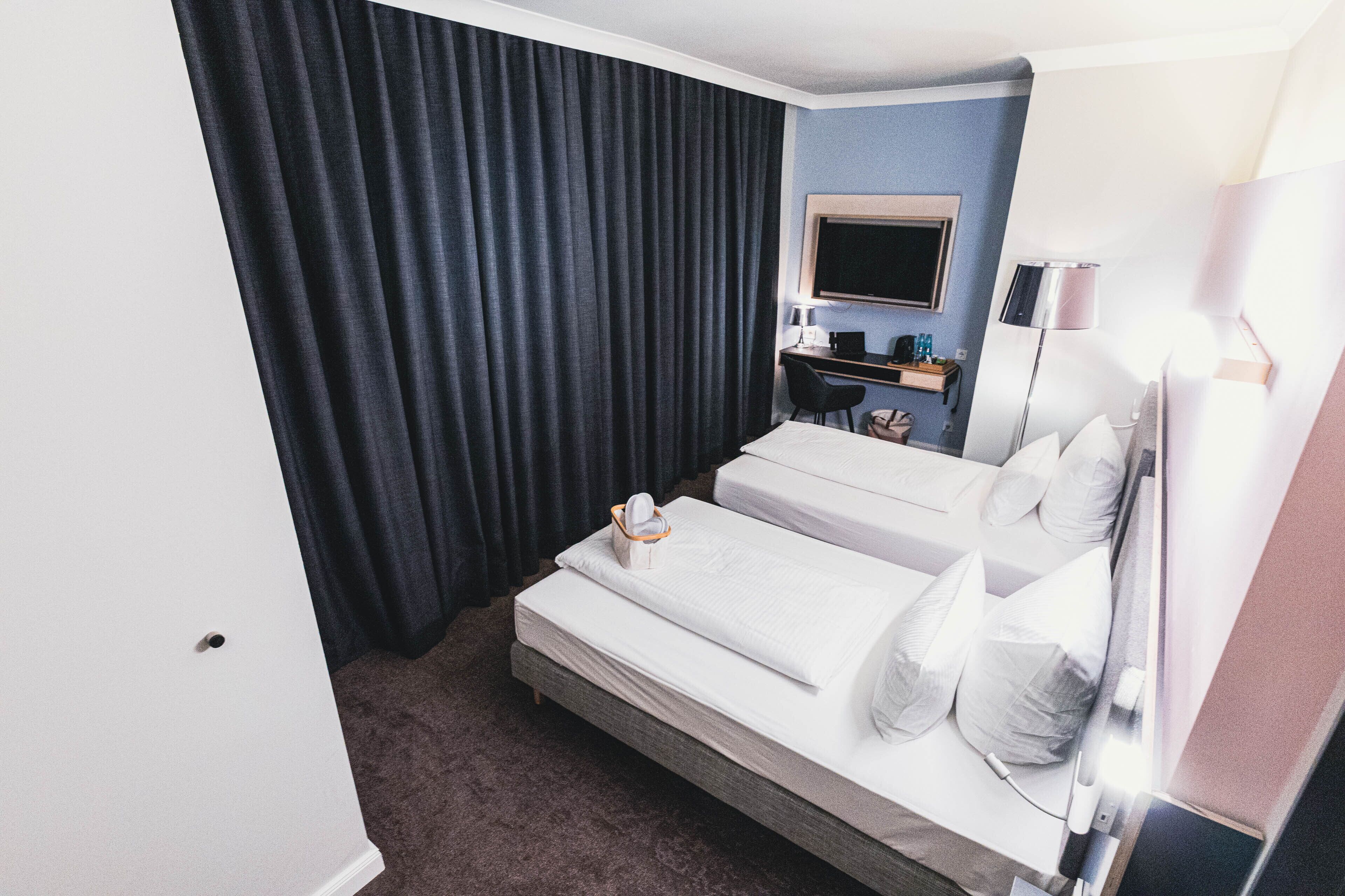 Habitación de hotel con dos camas, un escritorio, un televisor y una lámpara.