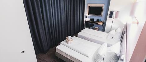 Habitación de hotel con dos camas, un escritorio, un televisor y una lámpara.