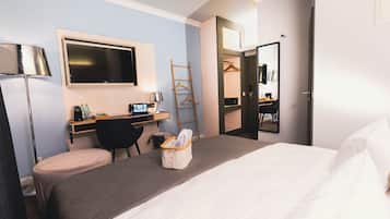 Habitación de hotel con cama, escritorio, silla y televisor.