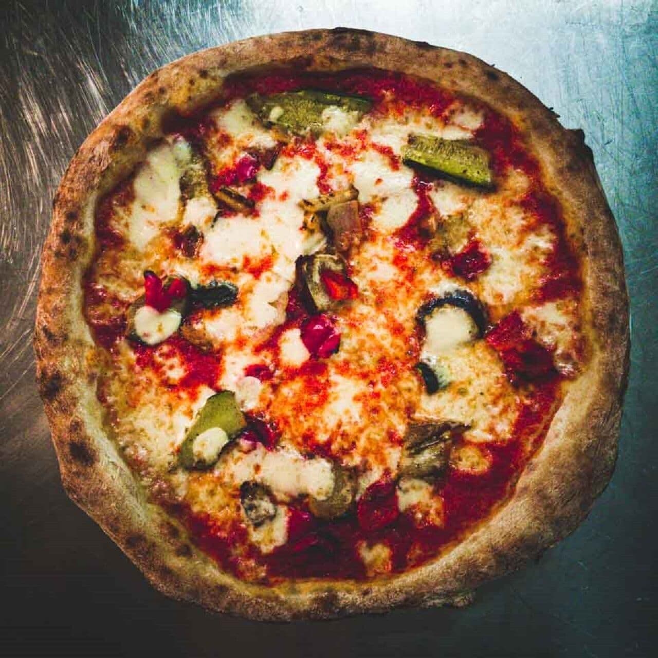 Eine Pizza mit verschiedenen Belägen auf einer Metallplatte.