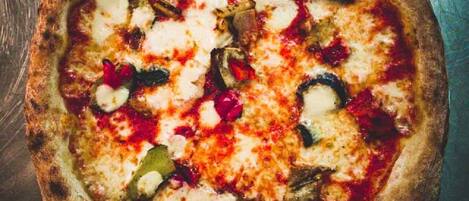 Una pizza con diferentes ingredientes sobre una superficie metálica.