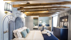 Camera d'albergo con un letto grande, una scrivania, uno specchio e una televisione.