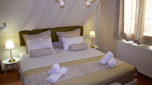 A neatly made bed with a headboard, two bedside lamps, and a window with curtains. - Elianthos Villa (Apokoronas)